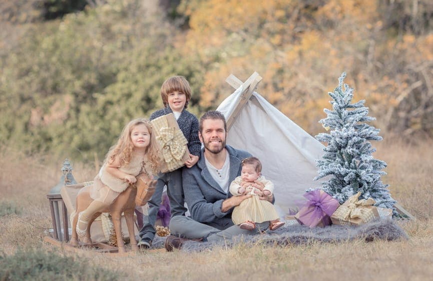 Celebrity blogger Perez Hilton with his children — Text Monster Cuban-American and Miami native Perez Hilton smiling outdoors with his three young children during a holiday-themed family photoshoot next to a small teepee tent and Christmas tree.